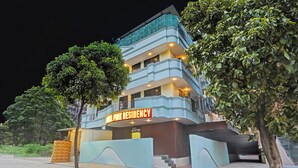 Un hôtel à plusieurs étages, doté d’un hall d’accueil et d’une enseigne indiquant « Hôtel Pink Residency ».