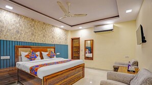 Une chambre d’hôtel avec un lit en bois, un mur à rayures bleues, un ventilateur de plafond et un appareil de climatisation.