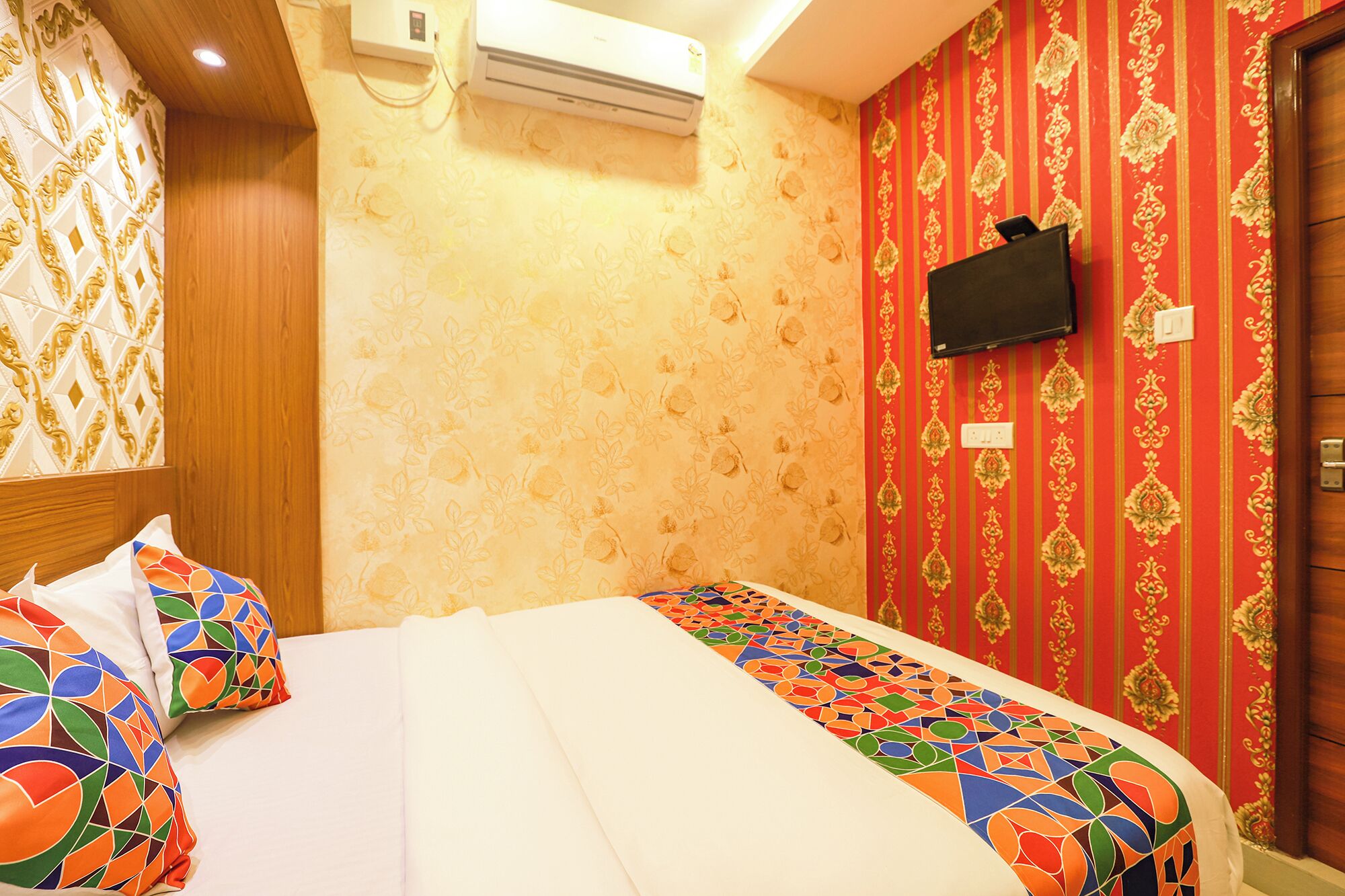 Een hotelkamer met een bed, een aan de muur bevestigde televisie en behang met een patroon.