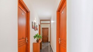 Un couloir avec des portes en bois, une plante en pot et des tableaux encadrés accrochés aux murs.