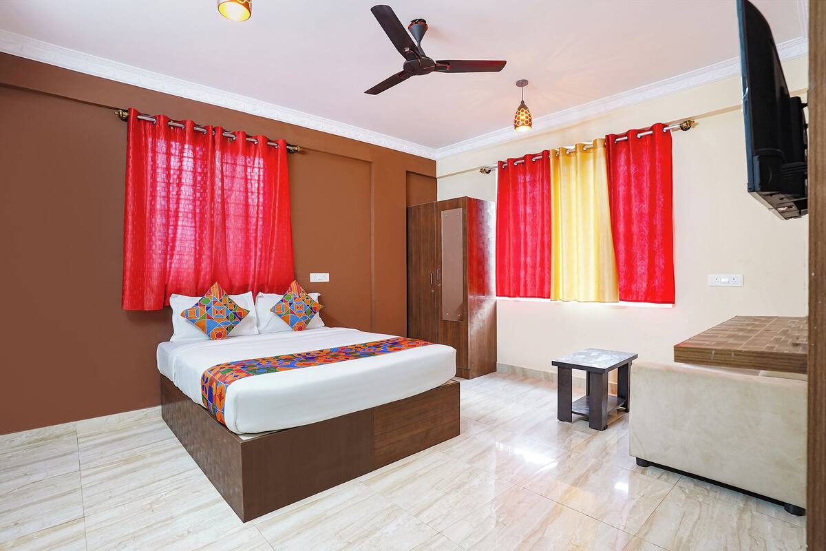 A bedroom with a bed, a wardrobe, a small table, and a ceiling fan.