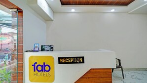 A reception desk at Fab Hotels with a wooden ceiling and a glass partition on the left.