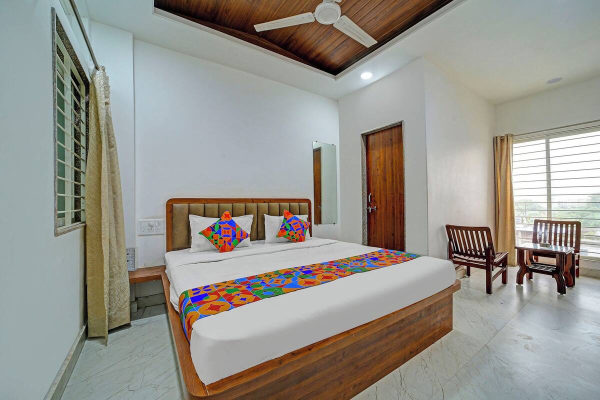 A bedroom with a wooden bed, a ceiling fan, a window with blinds, and a chair.