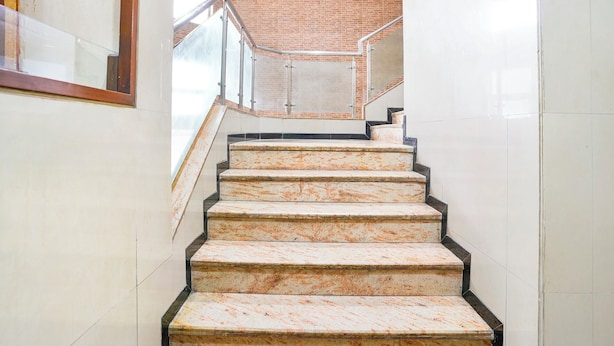 Un escalier en marbre avec des rampes en métal, menant à un mur de briques.