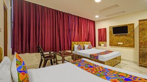 A hotel room with two beds, a small table, and a TV. - Fabhotel Golden Rivaah (Ghaziabad)