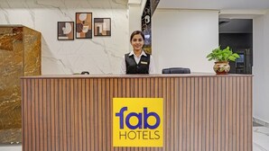 A reception desk with a 'fab hotels' sign, marble walls, and a potted plant. - Fabhotel Golden Rivaah (Ghaziabad)