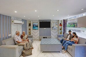 Un moderno vestíbulo de hotel con zona de estar, televisor de pantalla plana y vista al cartel del hotel.