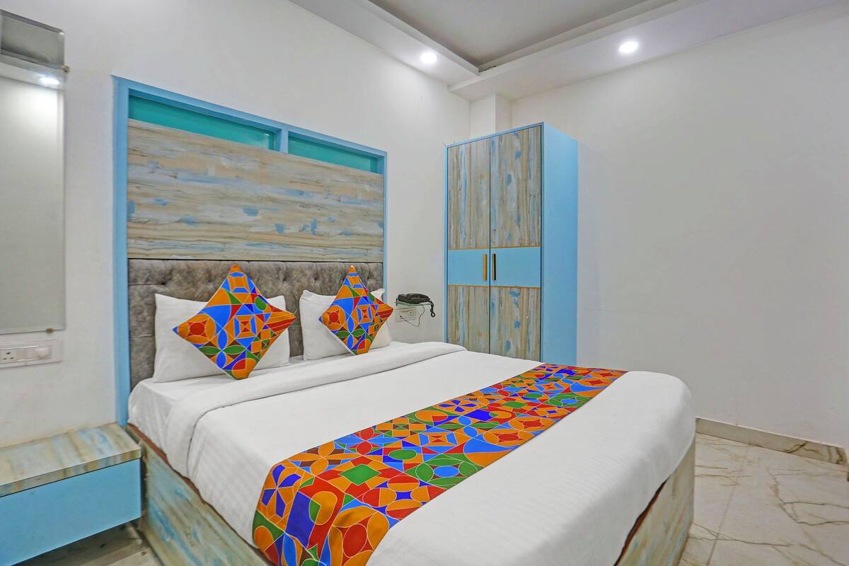 Ein Schlafzimmer mit einem Bett, einem Nachttisch, einem Kleiderschrank und einer Wand mit geometrischem Muster.