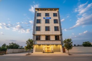Un hotel moderno de varios pisos con fachada plana, un llamativo letrero 'fabHOTELS' y una entrada bien iluminada.