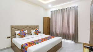 A modern bedroom with a large bed, a headboard, and a wooden wardrobe. - Fabhotel Shri Ram Retreat (Mathura)