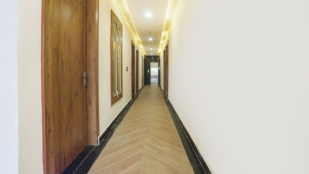 A long, narrow hallway with wooden doors on one side and a black-tiled floor. - Fabhotel Shri Ram Retreat (Mathura)