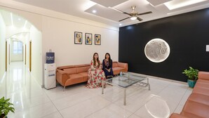 A modern lobby with a reception desk, a glass coffee table, and a large moon mural on the wall. - FabHotel Ayodhya Palace - Peenya (Bengaluru)
