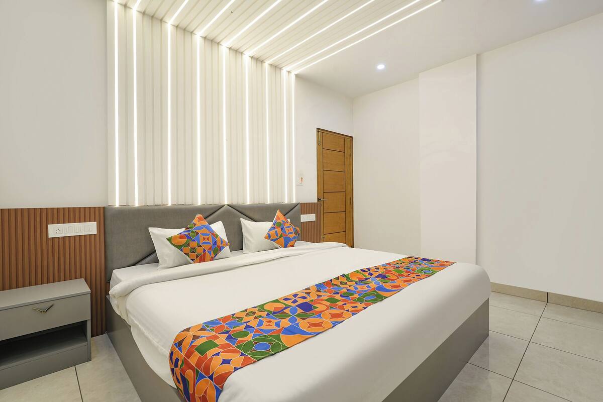 A modern bedroom with a bed, bedside tables, and a window with blinds.