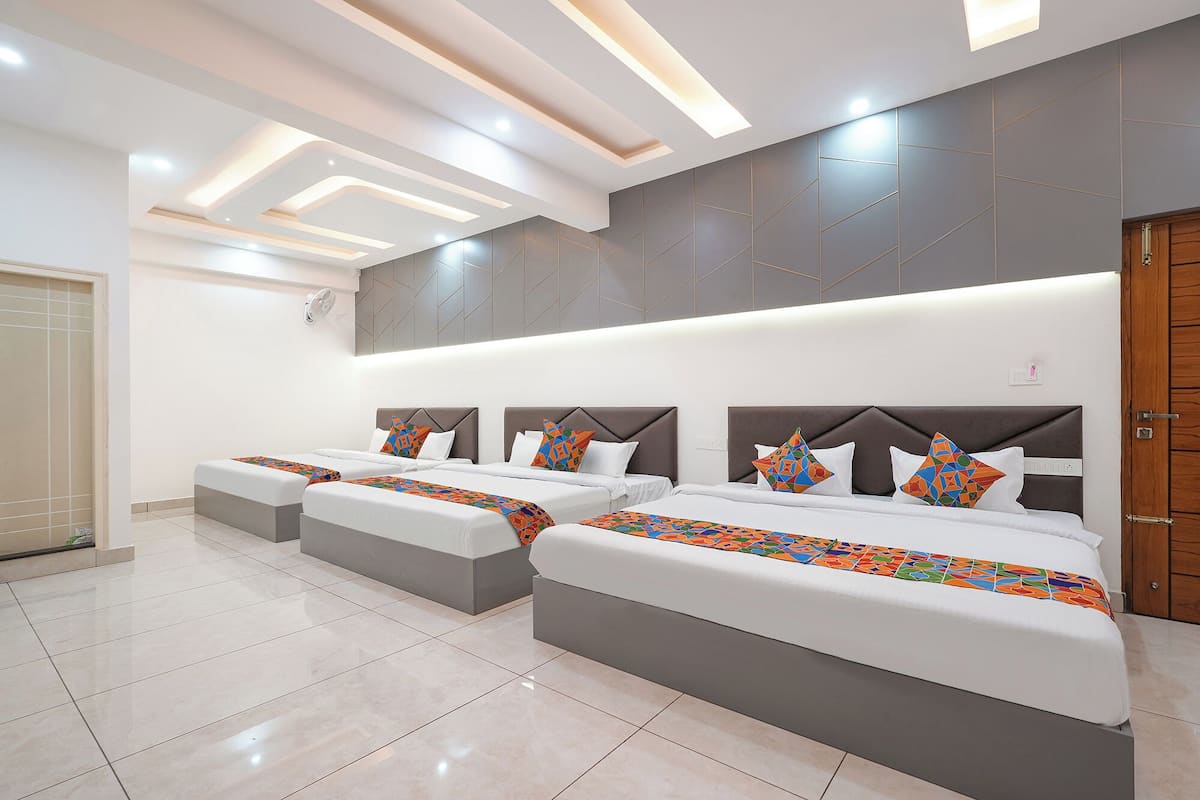 A modern hotel room with two beds, a large mirror, and a wooden door.