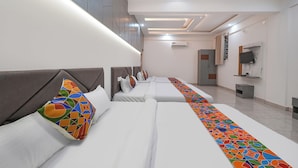 A hotel room with three beds, a TV, and an air conditioning unit. - FabHotel Ayodhya Palace - Peenya (Bengaluru)