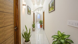A hallway with wooden doors, potted plants, and framed pictures on the walls. - FabHotel Ayodhya Palace - Peenya (Bengaluru)