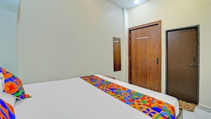 Una habitación de hotel con una cama, una puerta de madera y un cartel en la pared.