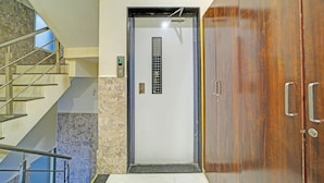 A modern elevator with a digital display, a marble wall, and a wooden door. - Fabhotel Grand Stay Ambedkar Nagar (Indore)