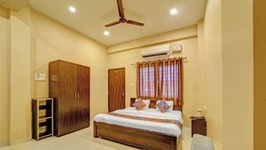A bedroom with a bed, a wardrobe, a ceiling fan, an air conditioning unit, and a bedside table. - Fabhotel Grand Stay Ambedkar Nagar (Indore)