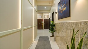 A hallway with a marble wall, a potted plant, and a framed artwork. - Fabhotel Grand Stay Ambedkar Nagar (Indore)