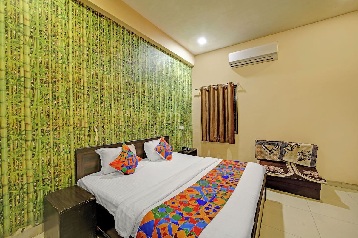 A hotel room with a bed, a chair, a curtain, and a wall with a bamboo pattern.