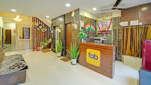 A hotel reception area with a reception desk, a clock, and a ceiling fan. - Fabhotel Grand Stay Ambedkar Nagar (Indore)