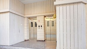 An entrance with a wooden facade, two elevators, and a sign indicating the name of the building. - Fabhotel Siddarth Prime (Penumuluru)