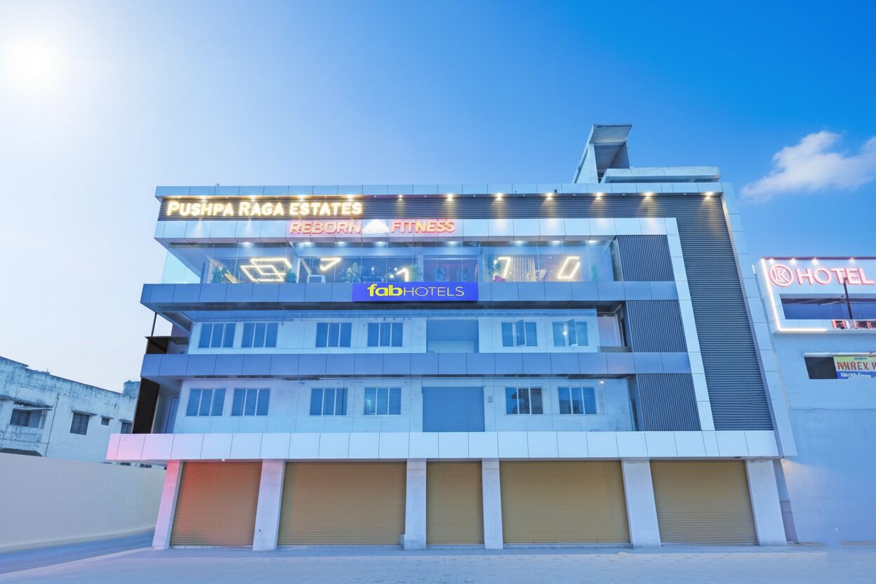 A multi-story building with signage for Pushpa Raga Estates, Reborn Fitness, and Fab Hotels.