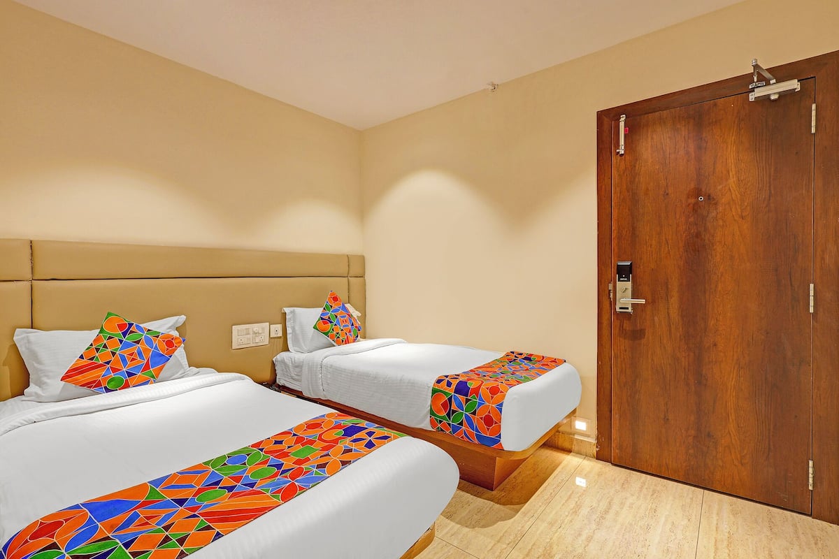 A hotel room with two beds, each with a colorful geometric-patterned bedspread.