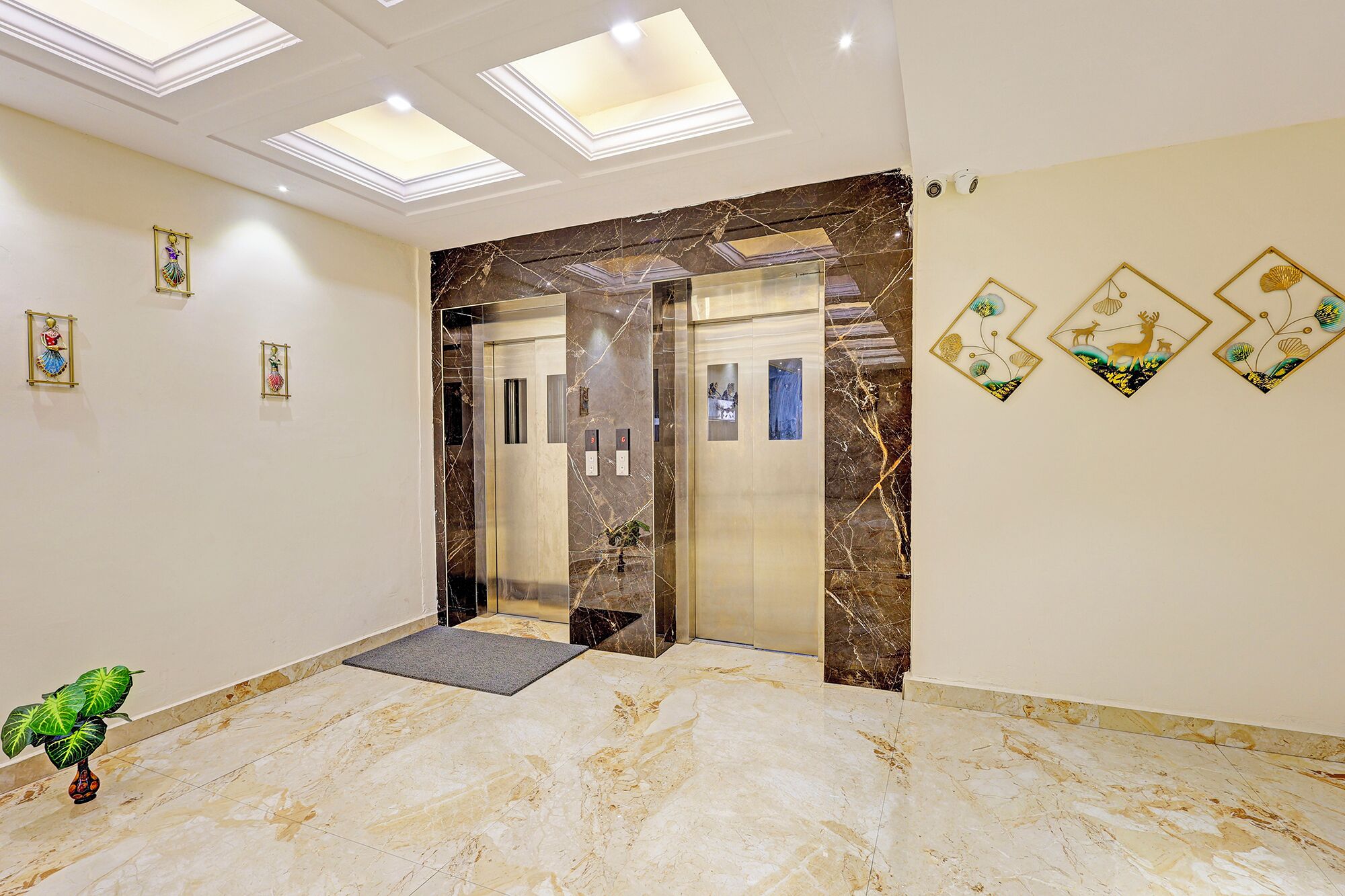 Een hotellobby met een marmeren vloer, een lift en kunst aan de muur.