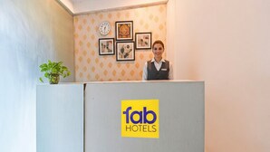 Ein Empfangsbereich mit einem 'fab hotels'-Schild, einer Uhr und gerahmten Kunstwerken an der Wand.