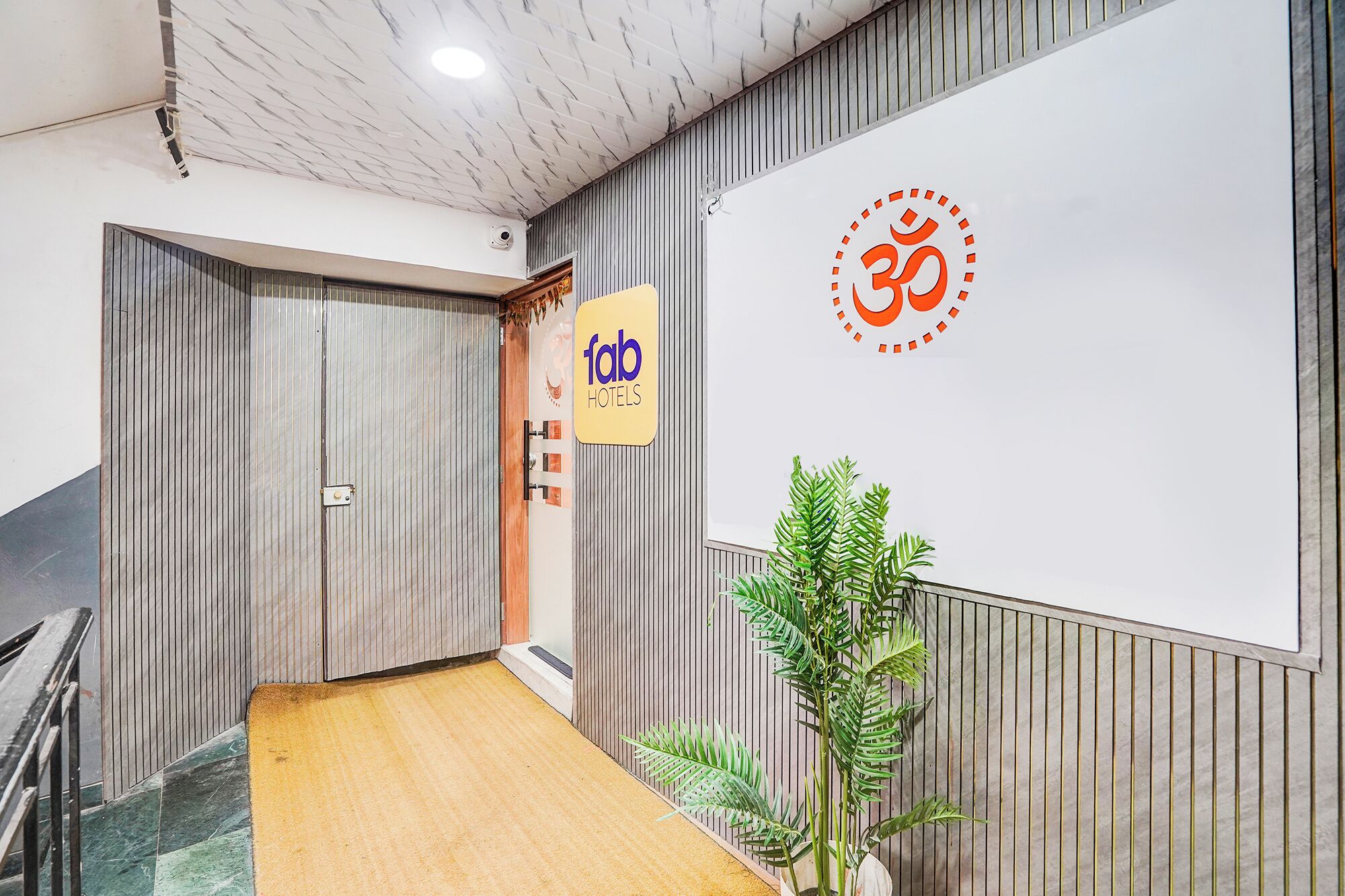 Un hall d’accueil d’hôtel avec un plancher en bois, un comptoir d’accueil, un panneau mural affichant le logo de l’hôtel et un grand mur orné d’un emblème circulaire.