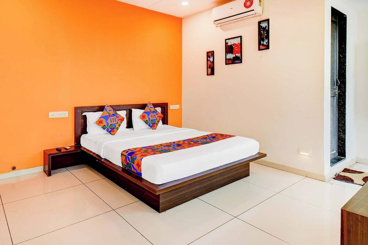 A hotel room with a large bed, orange walls, and a tiled floor.