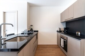 Een moderne keuken met een zwart aanrecht, een roestvrijstalen spoelbak en een inbouwoven.