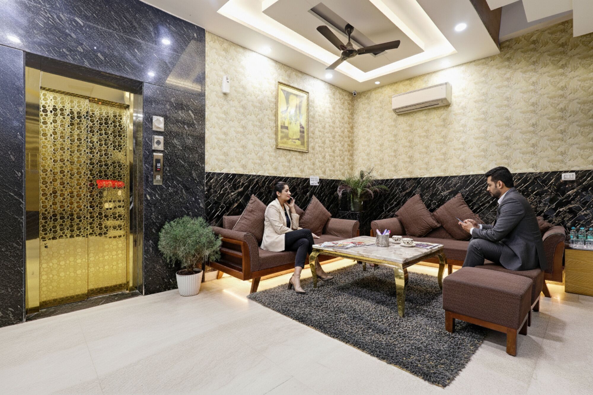 A lobby with a marble reception desk, a ceiling fan, and a seating area with sofas and a coffee table.