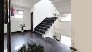 A modern interior with a staircase, potted plants, and a fire extinguisher. - FabHotel Church View - 500m from New Delhi Railway Station (New Delhi)