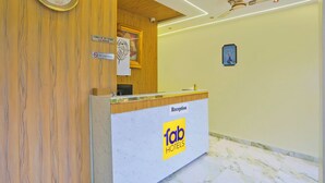 Un comptoir d’accueil avec une horloge, un panneau « Interdiction de fumer » et un panneau indiquant l’heure d’enregistrement : « Enregistrement à partir de midi ».