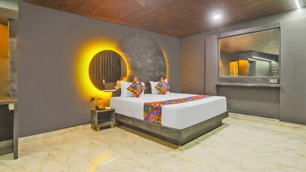 Une chambre moderne avec un grand lit, un miroir rond et une petite table de chevet.