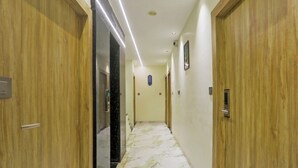 Un couloir avec des portes en bois, un sol en marbre et un plafond doté d’un éclairage encastré.
