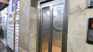 Um elevador com acabamento metálico e painéis de vidro decorativos.