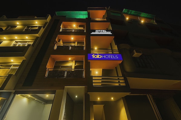 A multi-story hotel with balconies, a sign for 'Tab Hotels,' and a 'Hotel Hari Nagar Ashram' sign indicating available rooms.