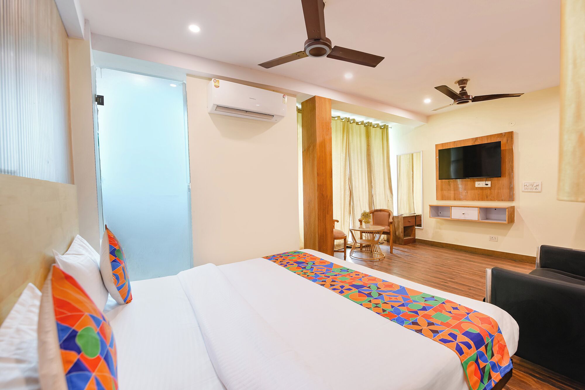 Une chambre d’hôtel équipée d’un lit, d’un bureau, d’une chaise, d’un téléviseur fixé au mur et d’un ventilateur de plafond.