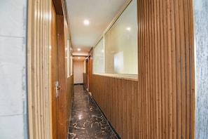 A corridor with wooden paneling, a marble floor, and a large window on the right.