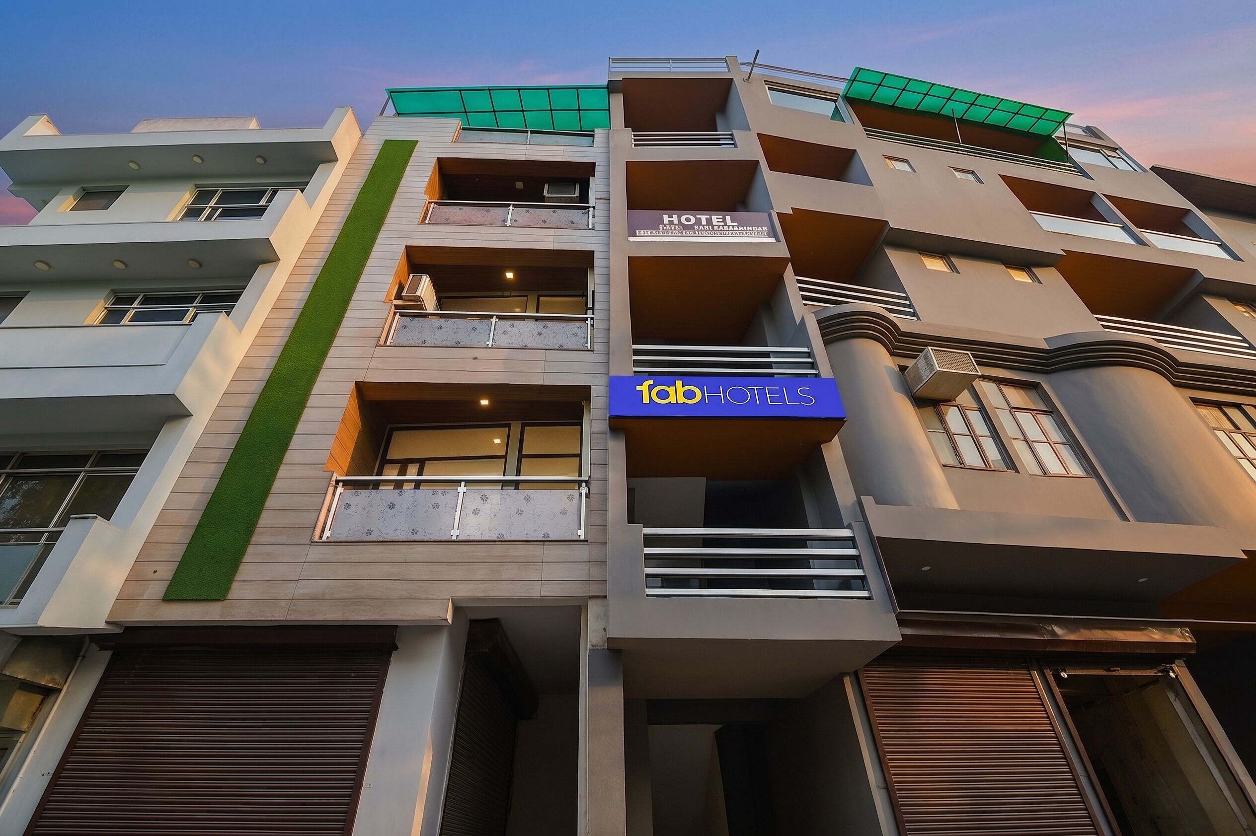 A multi-story hotel with balconies, a sign reading 'fabHOTELS,' and a green awning.