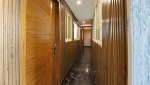 Corredor com painéis de madeira e piso de mármore.