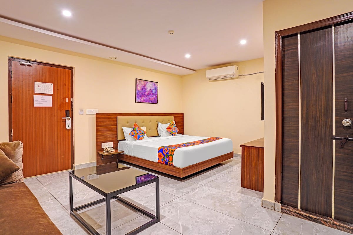 A hotel room with a bed, a bedside table, a desk, and a door.