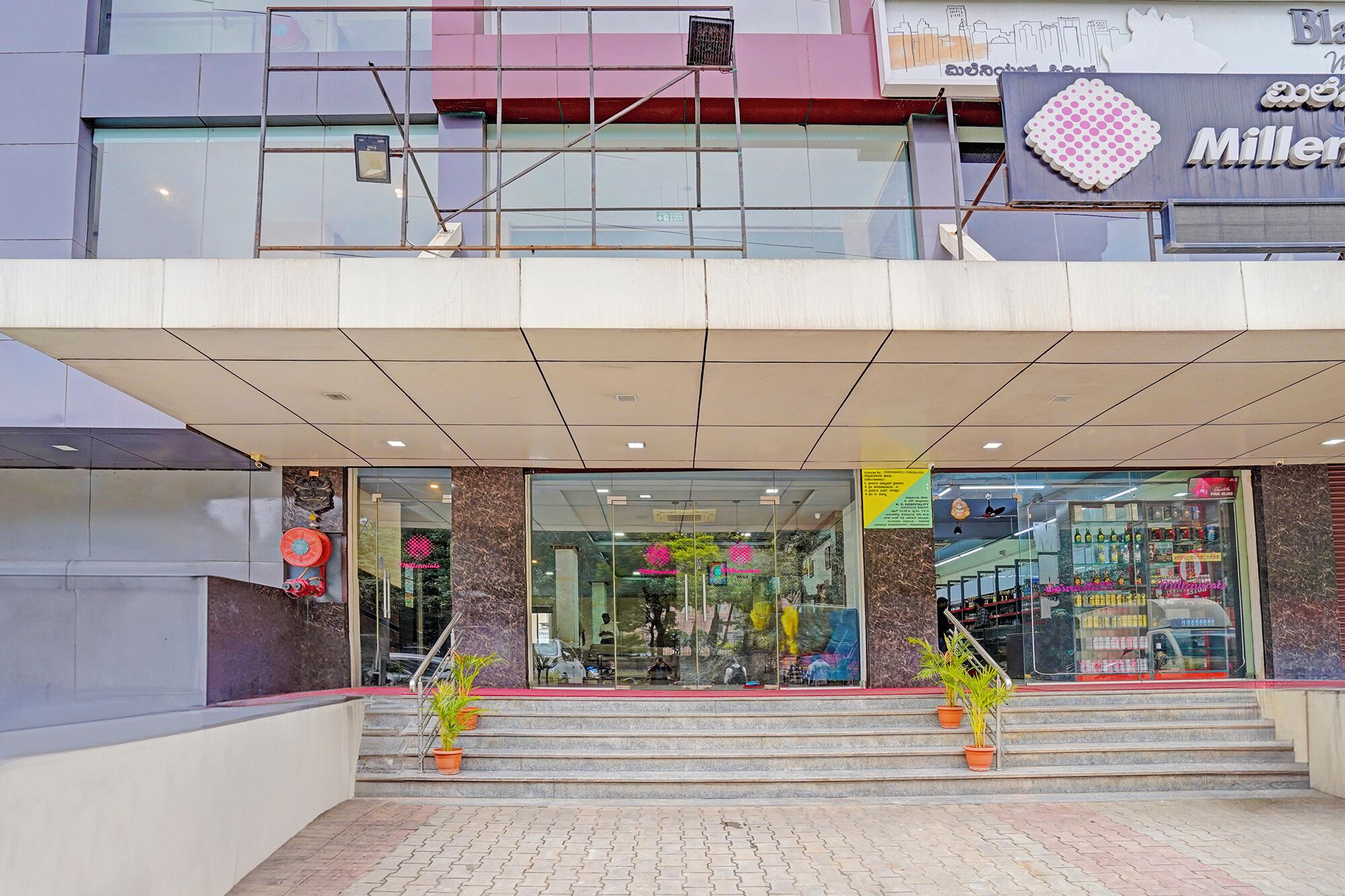 Une entrée moderne avec une façade en verre, des marches menant à l’entr ée et une enseigne au-dessus de la porte.