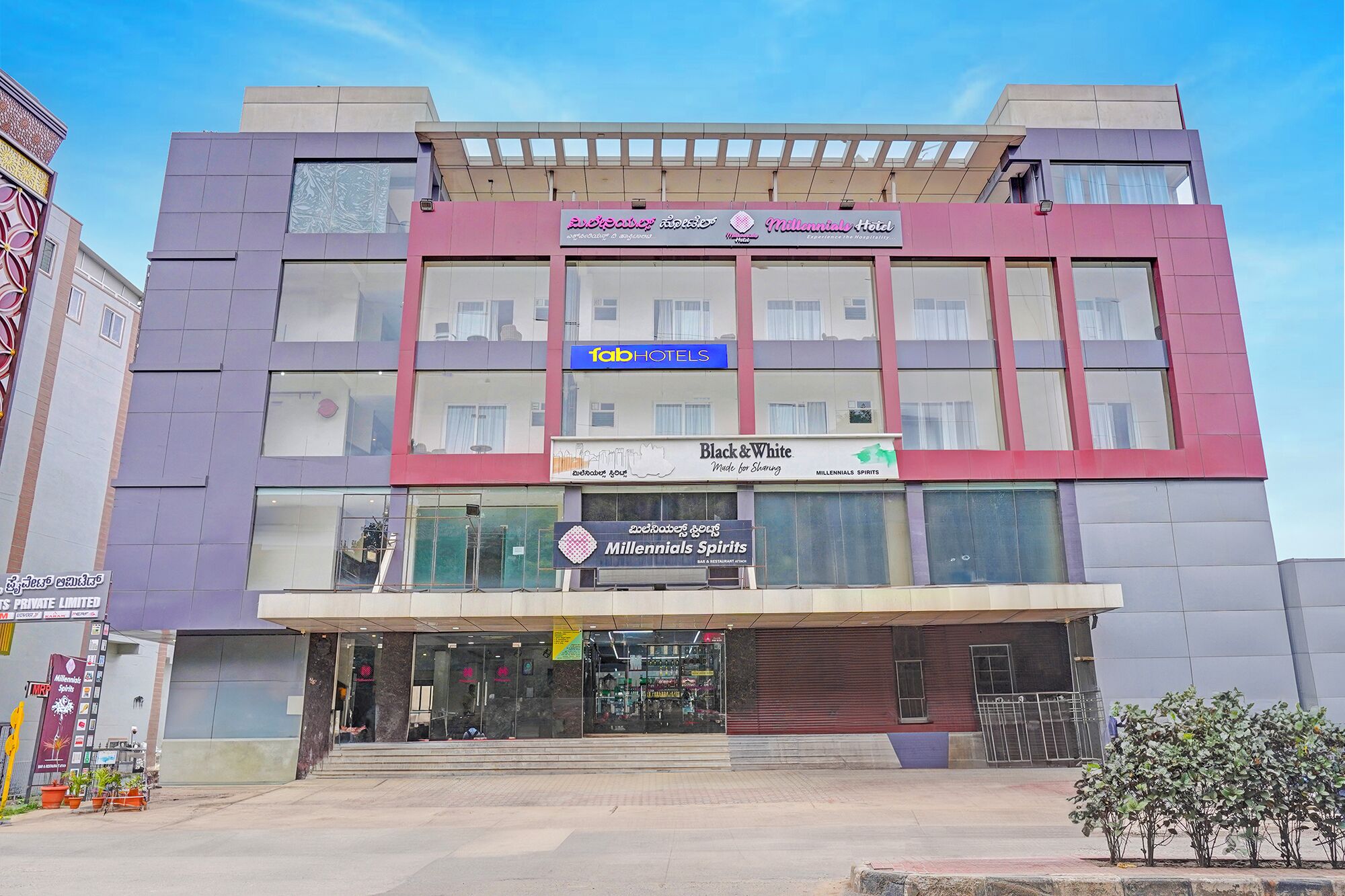 A multi-story hotel with signage for 'Millennials Hotel' and 'Black & White.'