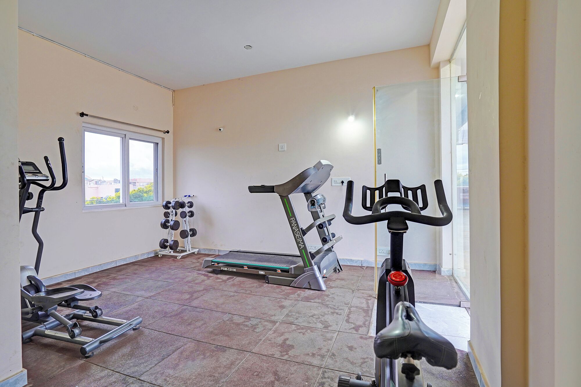 A home gym with exercise equipment including a treadmill, stationary bike, and weight bench.