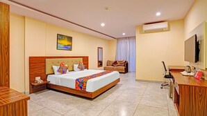 A hotel room with a large bed, a desk, a chair, a TV, and an air conditioner. - FabHotel Millennials - Jigani (Anekal)
